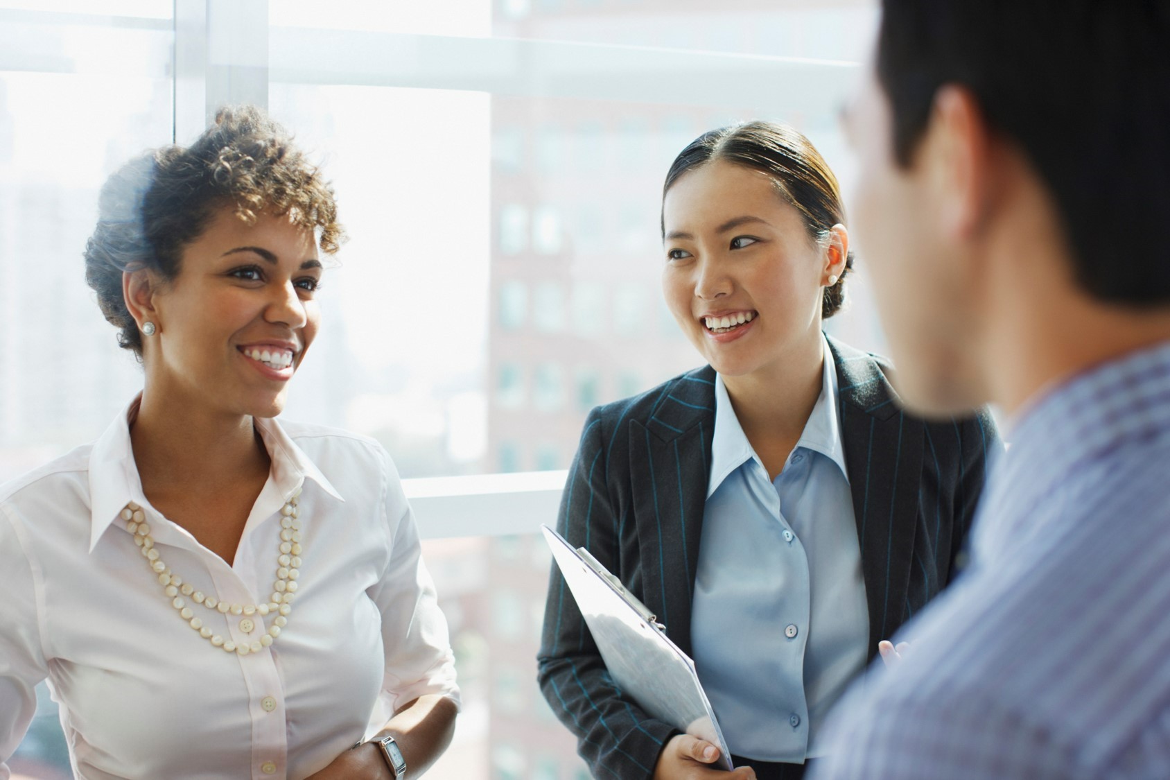 3 diverse associates converse in the office.