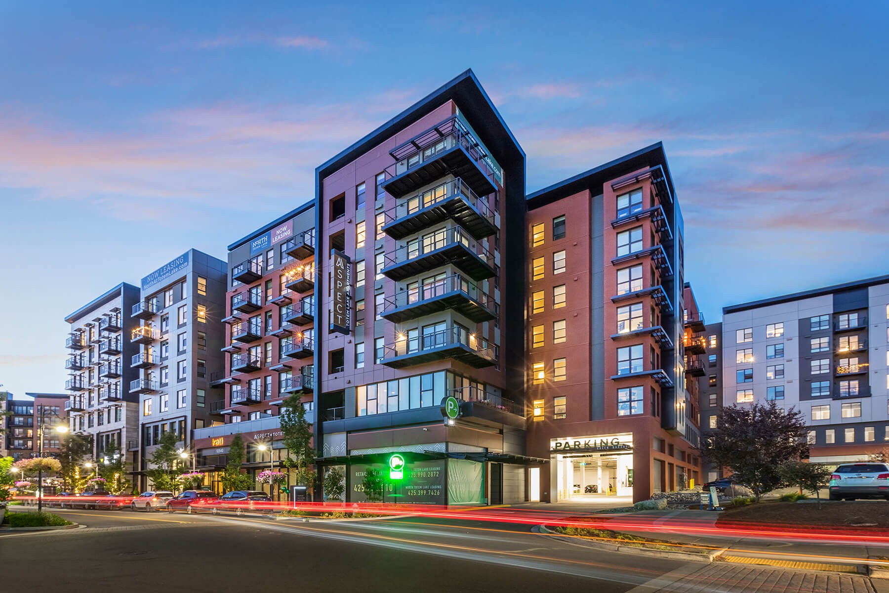 Up-looking view at Aspect at Totem Lake's exterior façade against a golden hour sky.