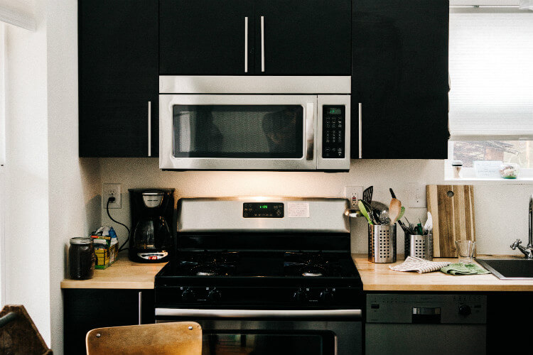 A close-up of a microwave and stovetop in a dark kitchen.