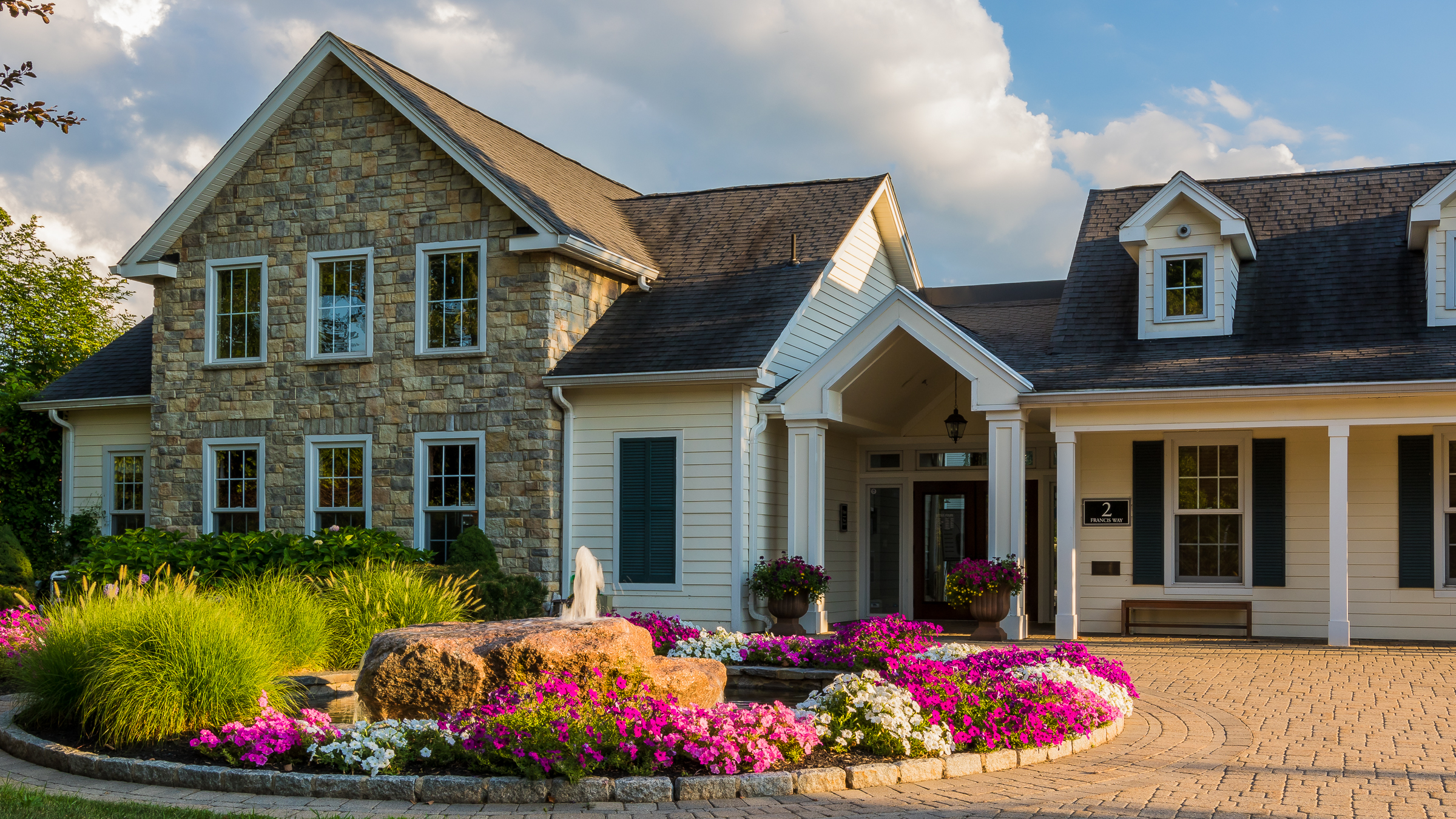 Exterior drive with garden circle leading up to Hawthorne at Gillette Ridge Apartments' leasing office