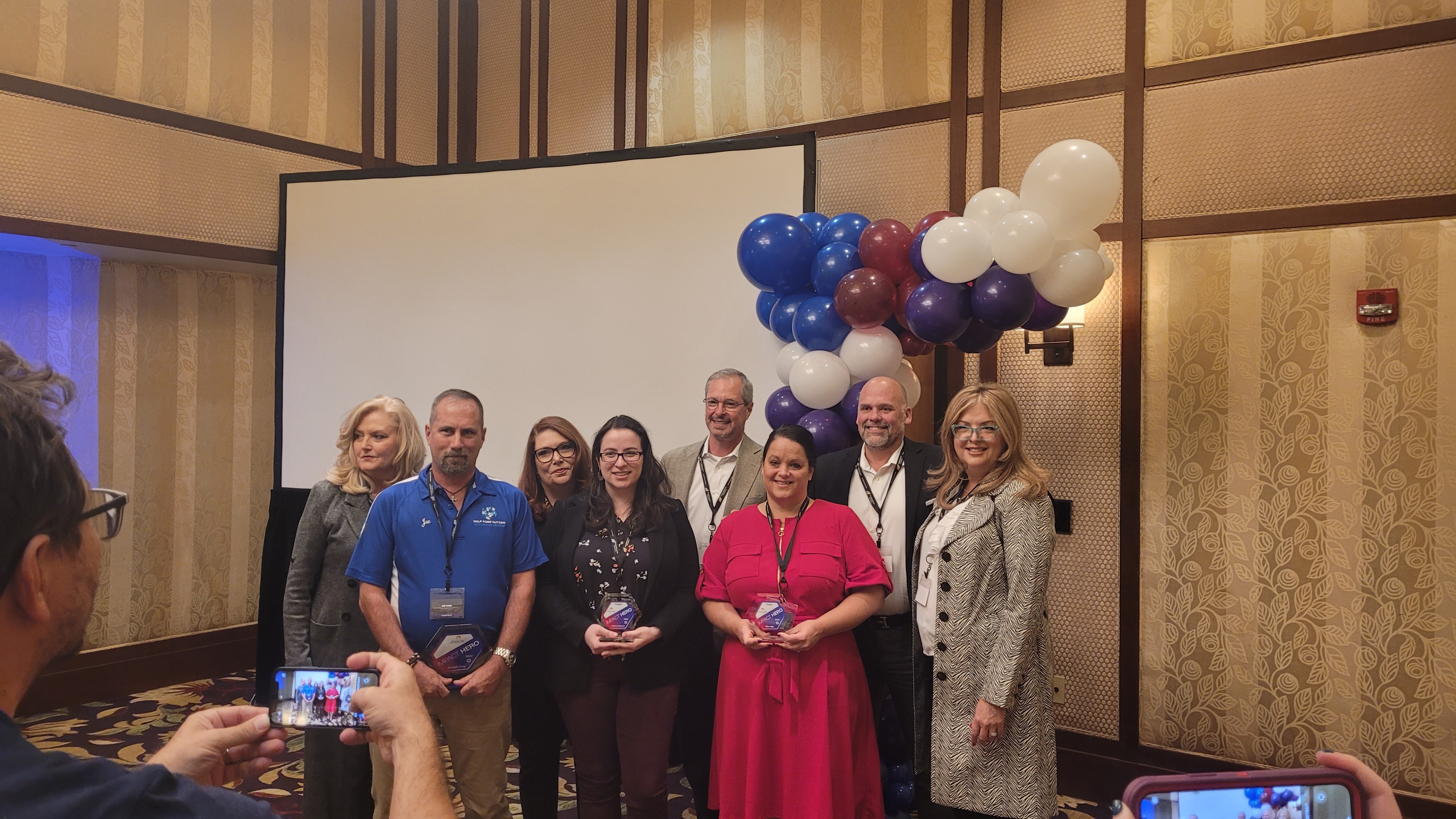 A group of Fairfield associates stand together to take a photo with their awards.